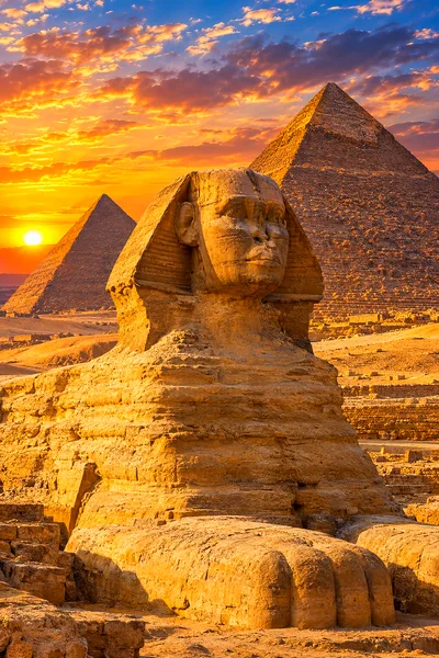 A hyper-detailed, photorealistic portrait diamond painting depicting a majestic stone sphinx before three towering pyramids at golden hour, with warm,
